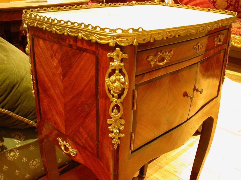 A Louis XV ormolu-mounted tulipwood and rosewood cabinet with marble top. The doors and drawer replaced.