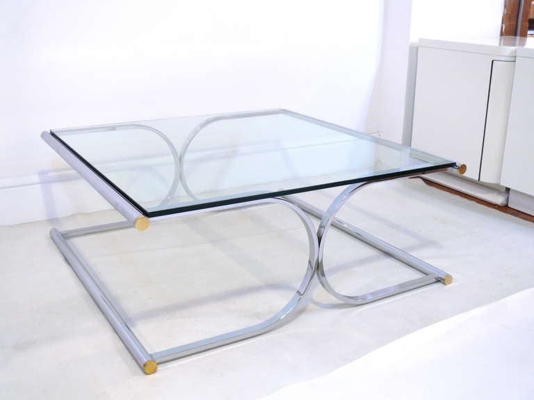 Stunning chrome and brass sculptural coffee table.  Flat bat stock mixed with ground create a timeless shape.  Tube ends are fitted with solid brass caps.  In excellent condition with new clear glass top.