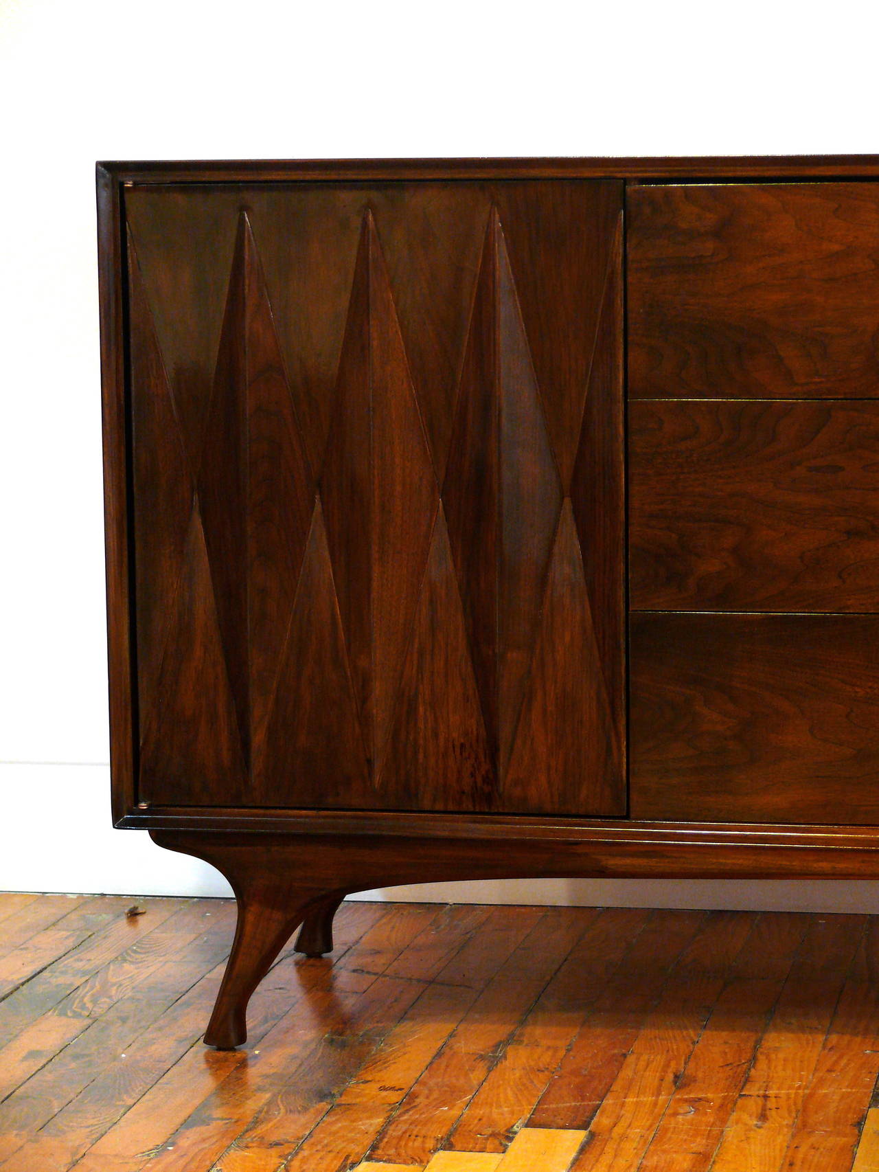 Fantastic Mid-Century dresser with gorgeous front diamond detailing, sculptural legs, finished in a rich high gloss medium walnut. It features three large middle drawers and three additional inner drawers behind each side door for plenty of storage.