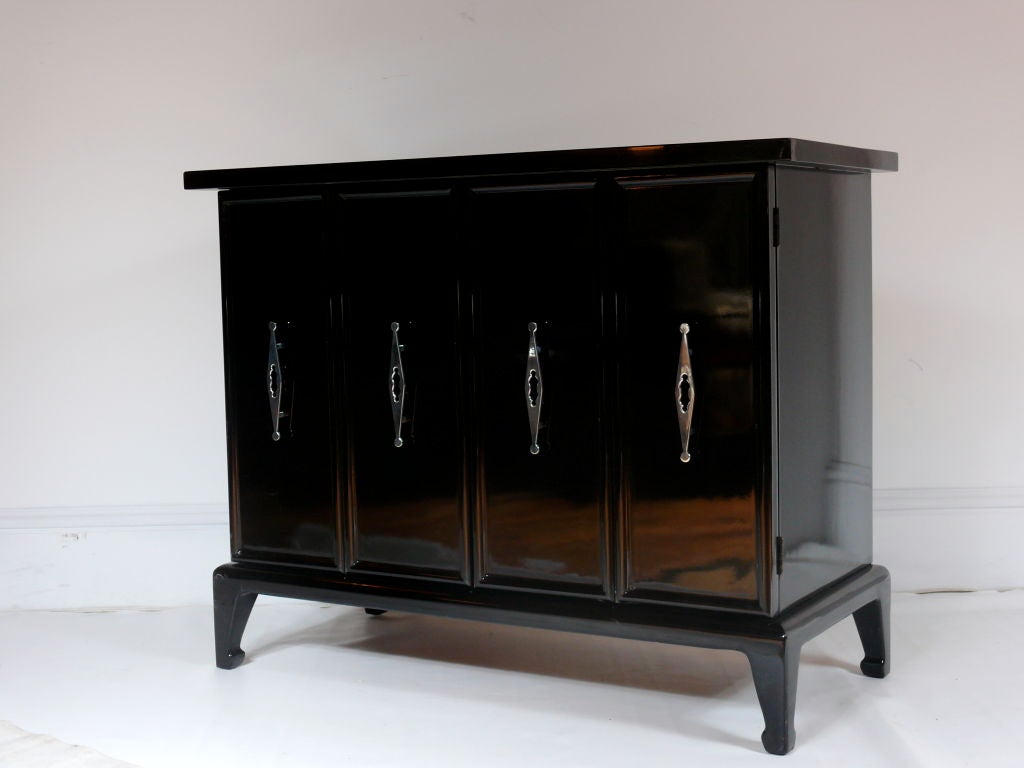 Pair of hand polished black cabinets with polished nickel hardware in the style of James Mont.  Bifold doors open to reveal shelves with ample storage.