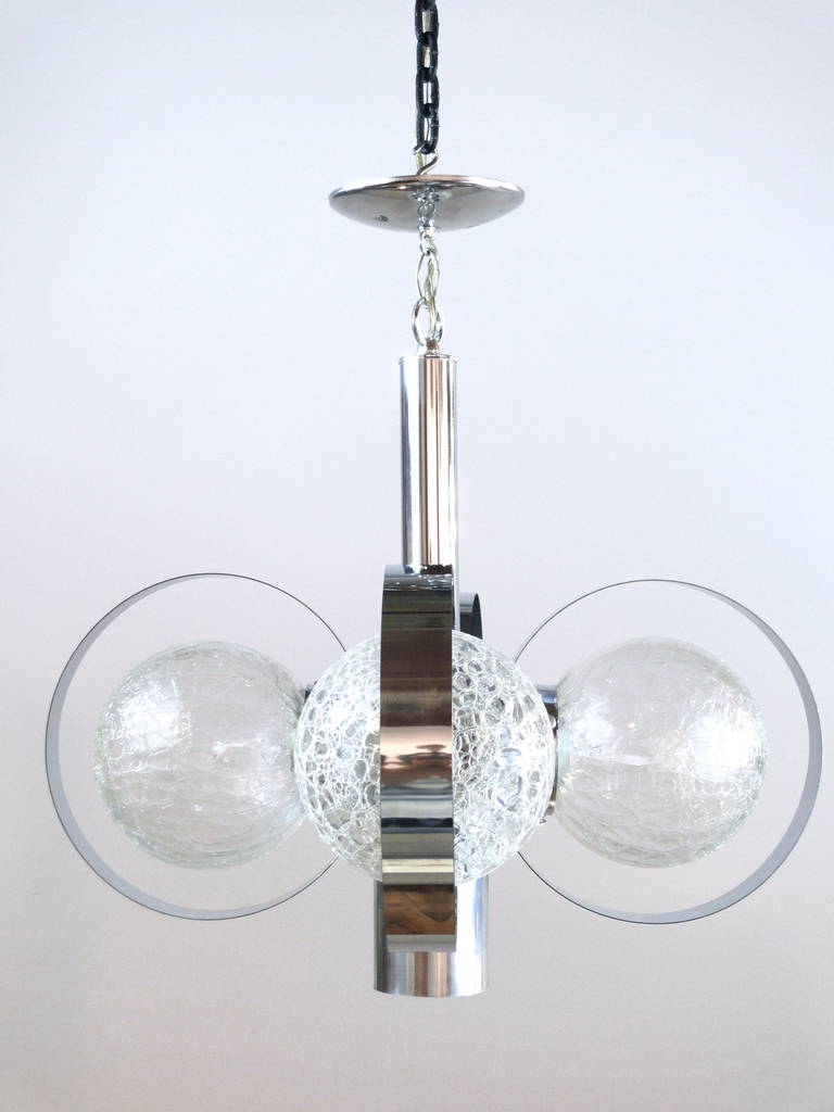 An exquisite pair of glistening crackled glass and chrome Mid-Century pendant chandeliers. The chrome frame has been polished to a gleaming perfection. Four rewired sockets illuminate the attaching globes with a fifth bottom socket for extra