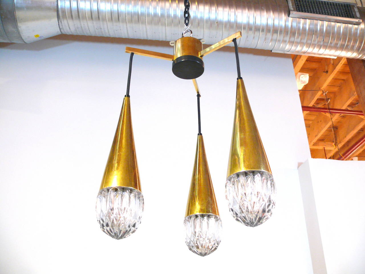 Elegant Mid-Century three-light hanging fixture By Kaiser Leuchten with dazzling ice glass domes, each hanging from a brass cone shaped three way frame.  Fixture has been fully rewired.