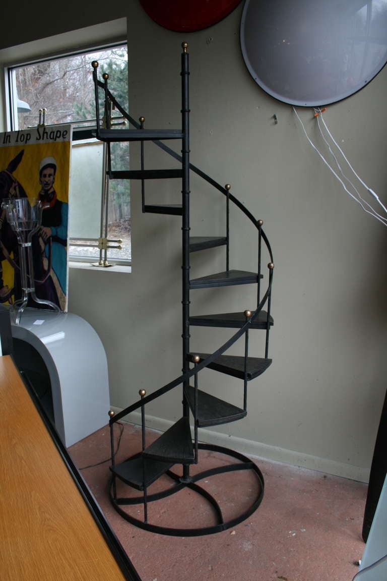 Iron spiral stairs with ebonized wood steps, fer forge faux bois detail on rails, brass finials.