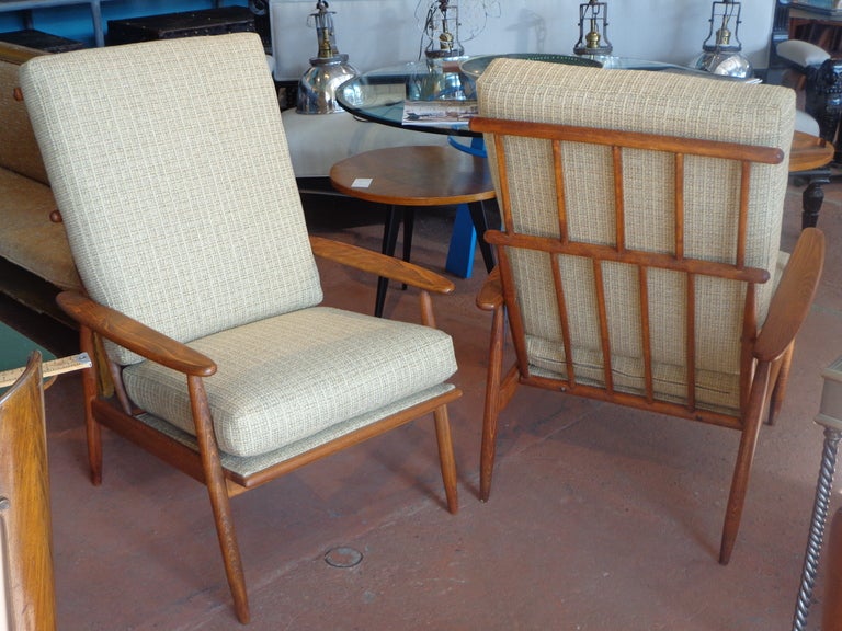 Unusual pair of solid teak armchairs with high spindle backs. All new webbing, upholstery and cushions in designer fabric. Chairs are unsigned.