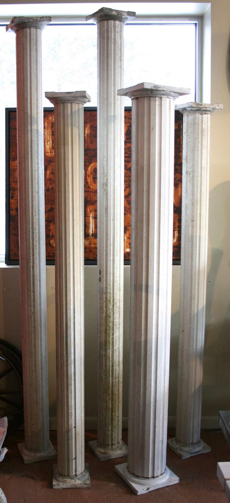 Group of five painted zinc columns, aged patina