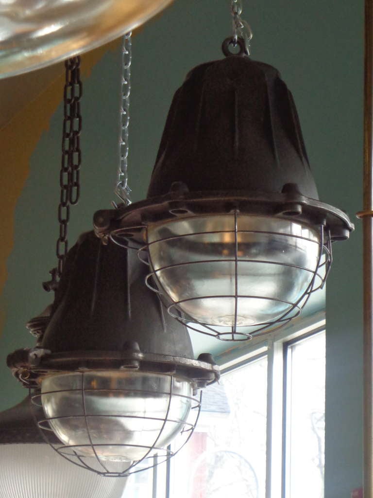 Pair of large cast iron french industrial hanging pendants, with original glass and wirework covering. Can be fitted with chain or poles.
