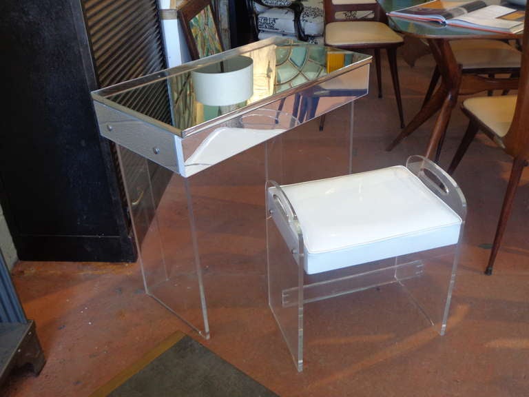 Fabulous lucite table with double-sided mirrored top, which flips up into vanity, lucite stool with original white patent leather/vinyl seat. Brass stud detail on sides, back and bench.