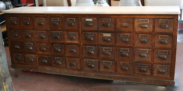 Very lovely substantial French apothecary sideboard with white fossil marble top, 40 drawers with original pulls and tag holders, beautiful vintage condition.