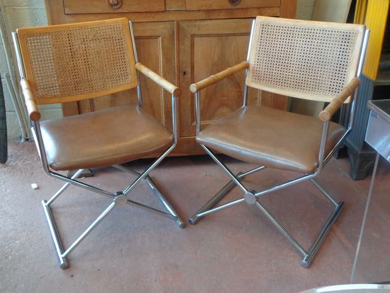 Pair of chrome chairs with solid wood faux bamboo arms, caned back, vinyl seats.