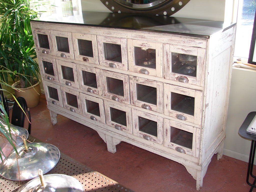 Early shop fitting, with 18 glass front drawers with original hardware, and blackened steel top.