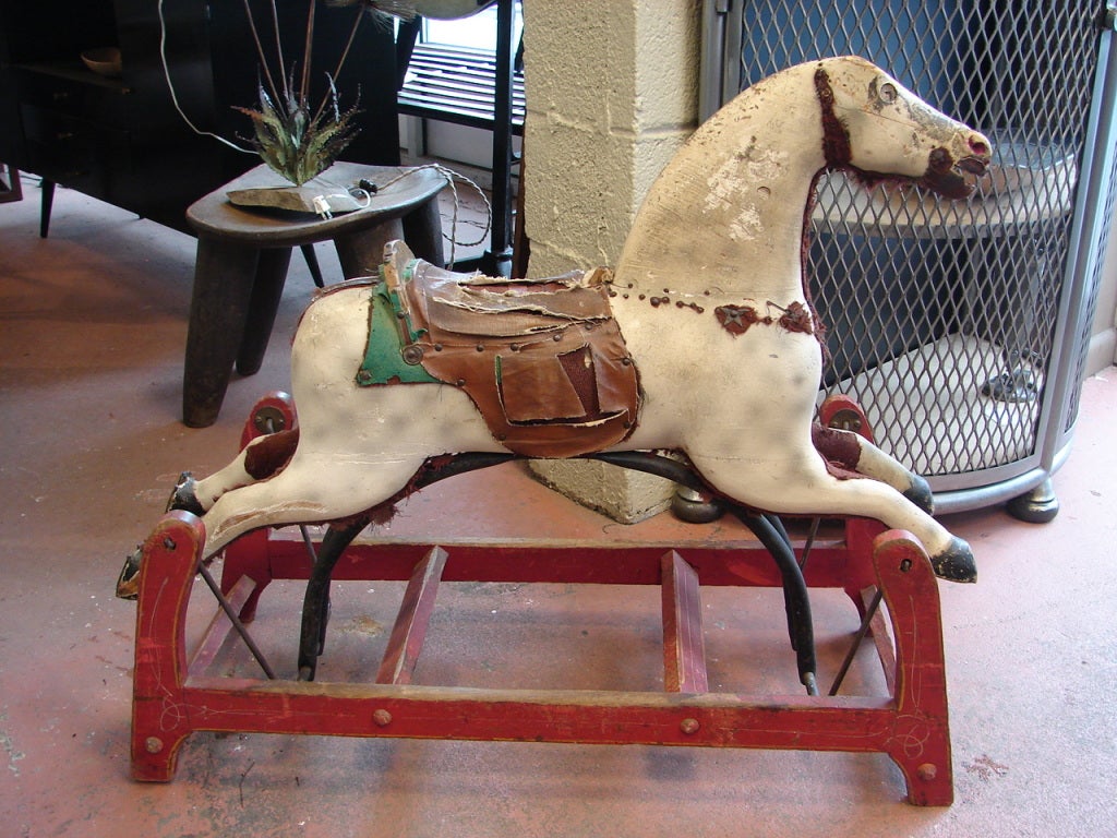 Charming painted wood horse on glider, with worn leather/canvas saddle and iron horseshoes on back hooves.