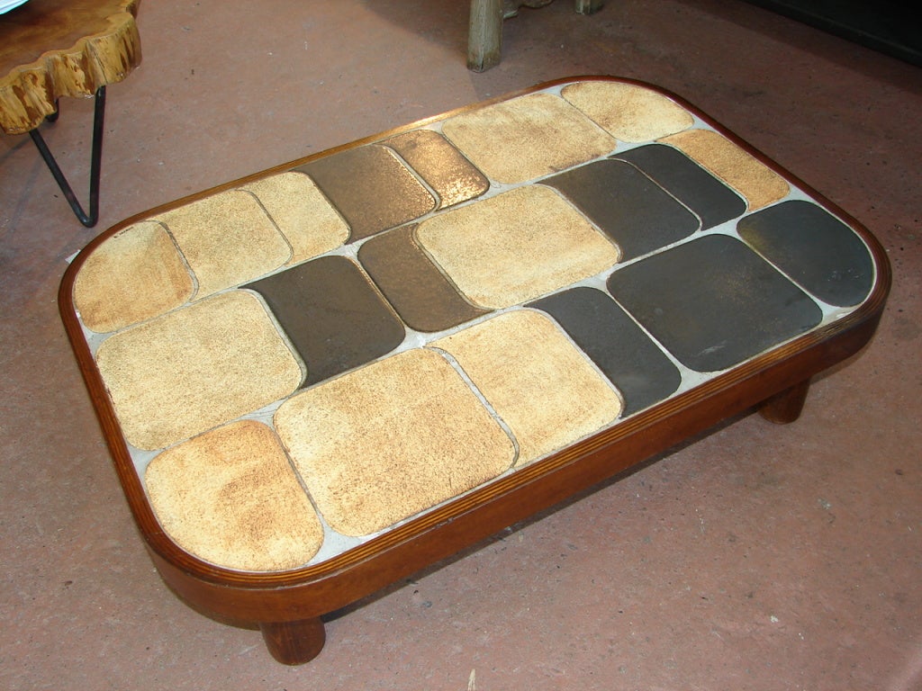 Glazed ceramic tile table top with molded wood frame and cylindrical legs, signed R. Capron