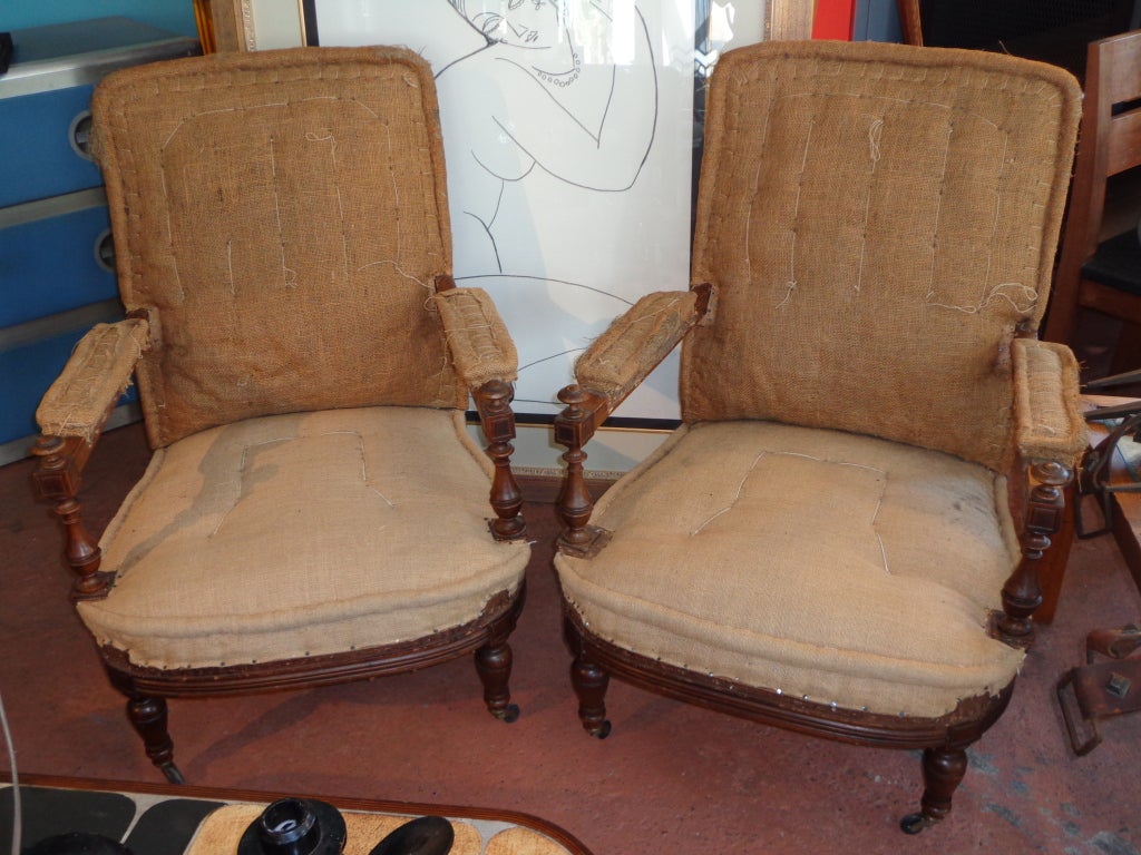 Pair of French armchairs with turned walnut wood arm supports and legs with castors. Deconstructed burlap/horsehair upholstery.