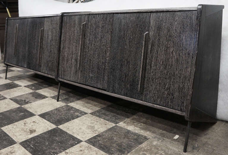 A northern Italian limed oak credenza featuring a highly unusual and striking design where the back legs are the body of the credenza itself. On the front there are 3 round iron legs. Door fold to the sides showing 3 drawers and four storage spaces