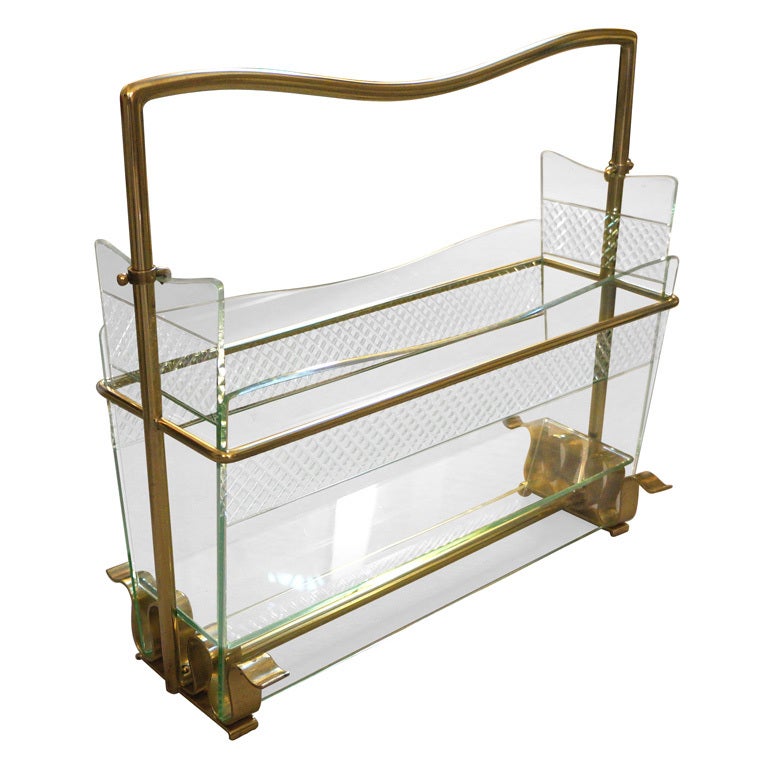 Elegant details are the main feature of this glass and brass magazine rack. Finely beveled glasses are held together by a brass structure.
