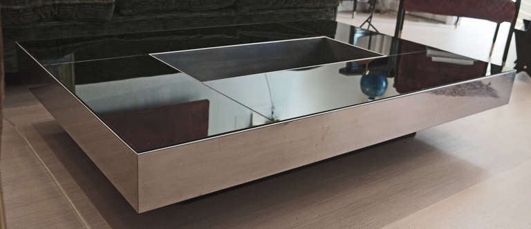 Notable design piece made in Italy in the 70's. The black base and the dark mirrors on top contrast with the steel.a wide receptacle in the middle of the table entirely lined in steel can be used for magazines or liquors and glasses