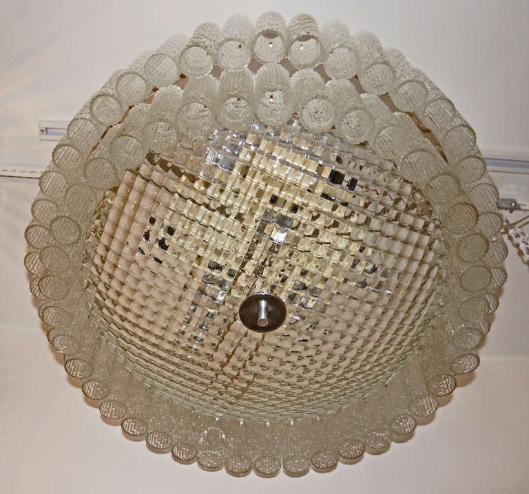 Large flush mount Murano glass glass chandelier. A  central,  reversed dome with a net pattern hides totally the six light bulbs attached to the metal structure. Two layer of tube shaped and ribber glasses cover and de