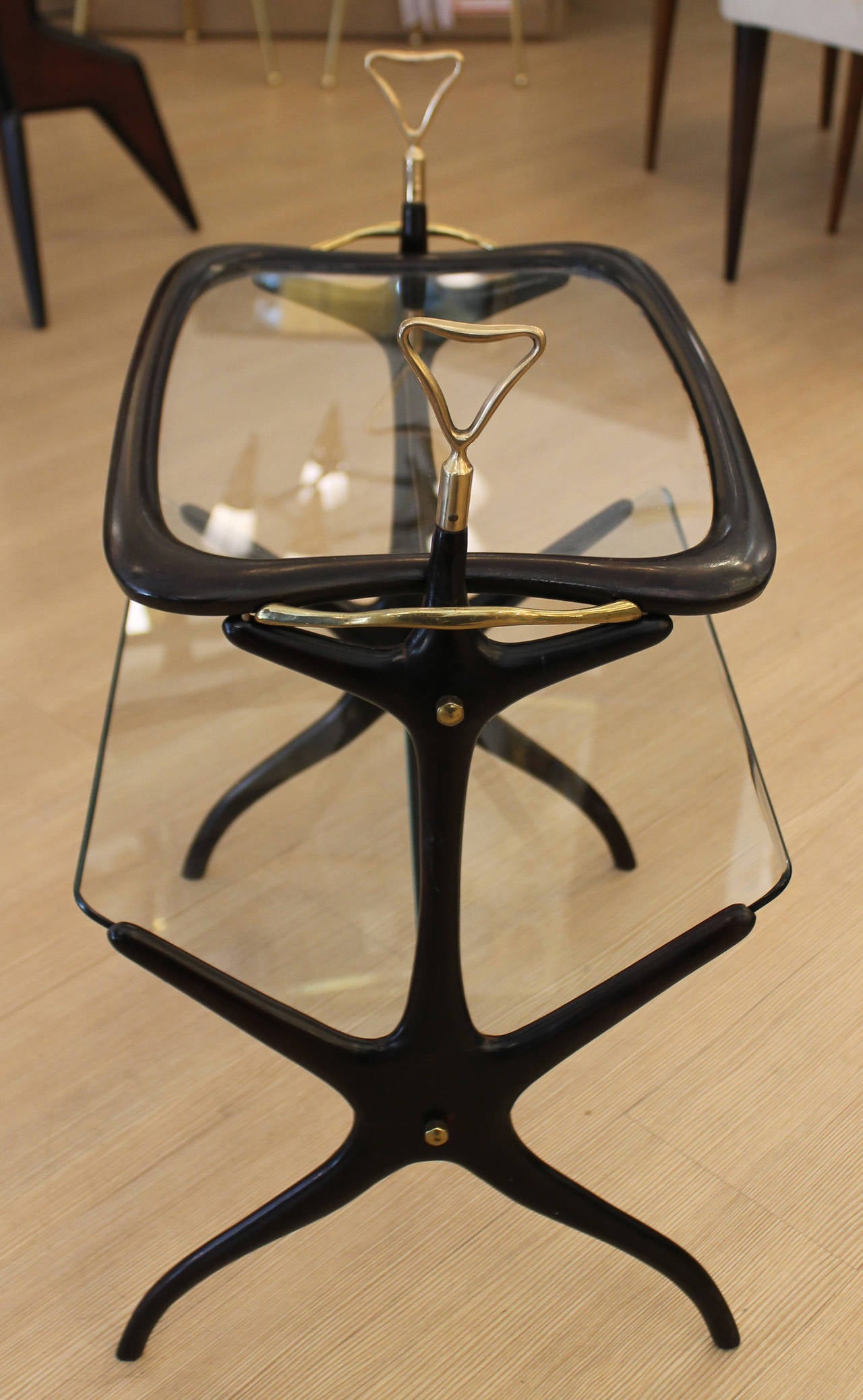 Elegant Italian Mid-Century side table that functions also as a magazine stand and drink serving tray. The top is a removable tray that fits through two brass handles in the table. The angular lower glass level is the magazine stand. Height of the