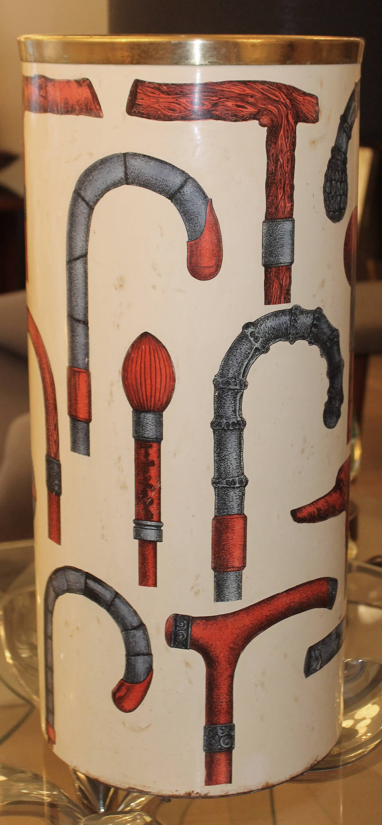 Whimsical as many of the great tromp l'oeil master creations, this umbrella stand plays with the theme of umbrella handles using blue and red handles on an ivory background. Brass-plated trim. Marked at the bottom. Literature: Fornasetti La Bottega