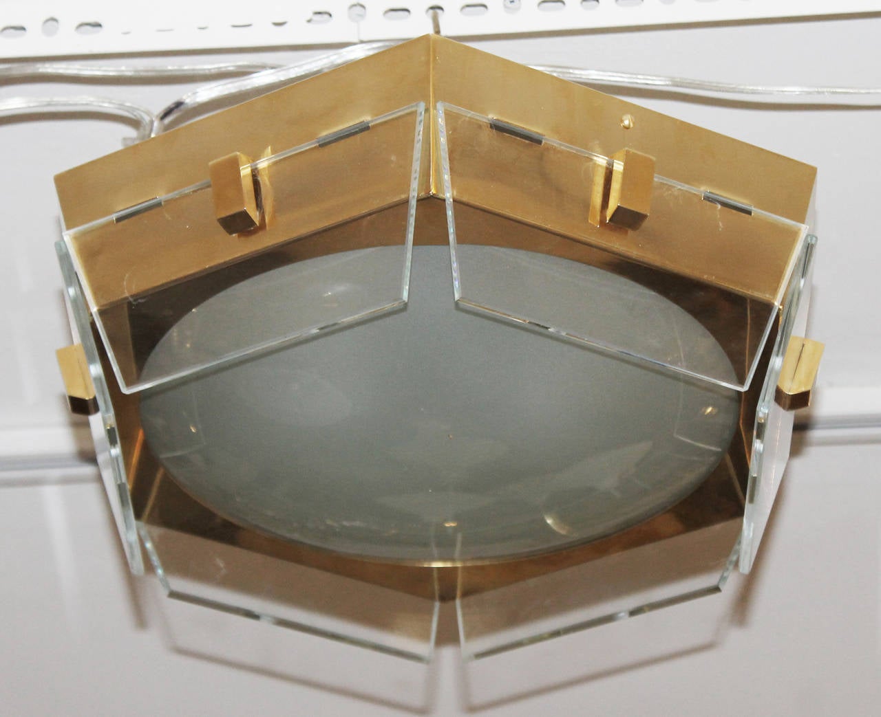 Brass and glass ceiling light. The hexagonal brass structure holds a convex frosted glass and one clear glass on each side. The brass structure has three candelabra lamp sockets.