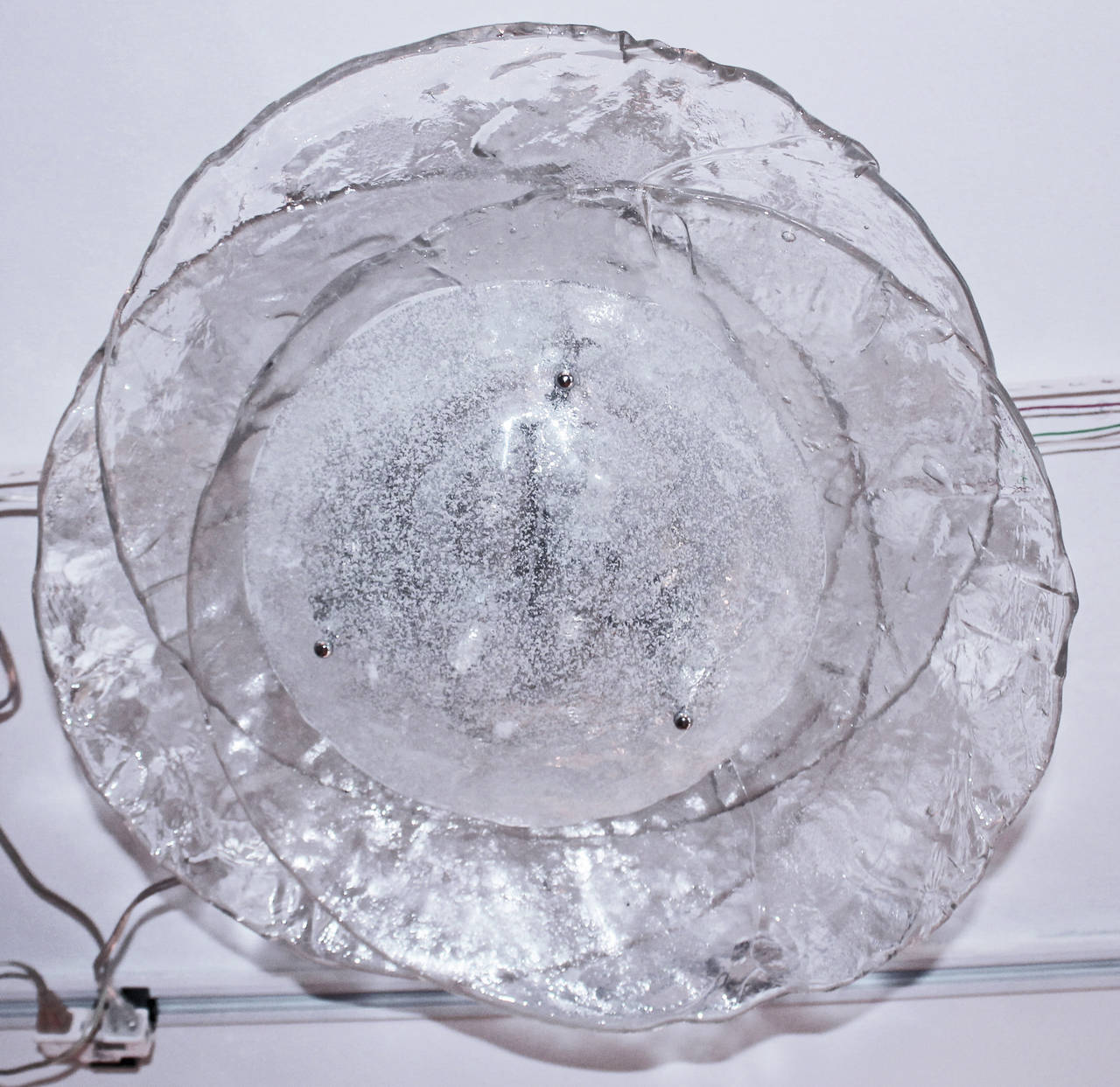 Very beautiful flush mount ceiling light made using three irregular clear handblown glass discs protruding in different directions. The area containing the lamp sockets is closed with a 