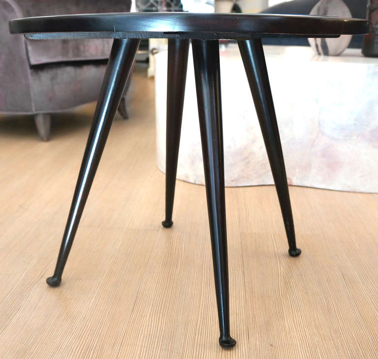 A quite unusual round side table featuring an ebonized wood structure supporting a nice blue back painted glass. Particularly nice is the shape of the four legs ending in rounded feet.