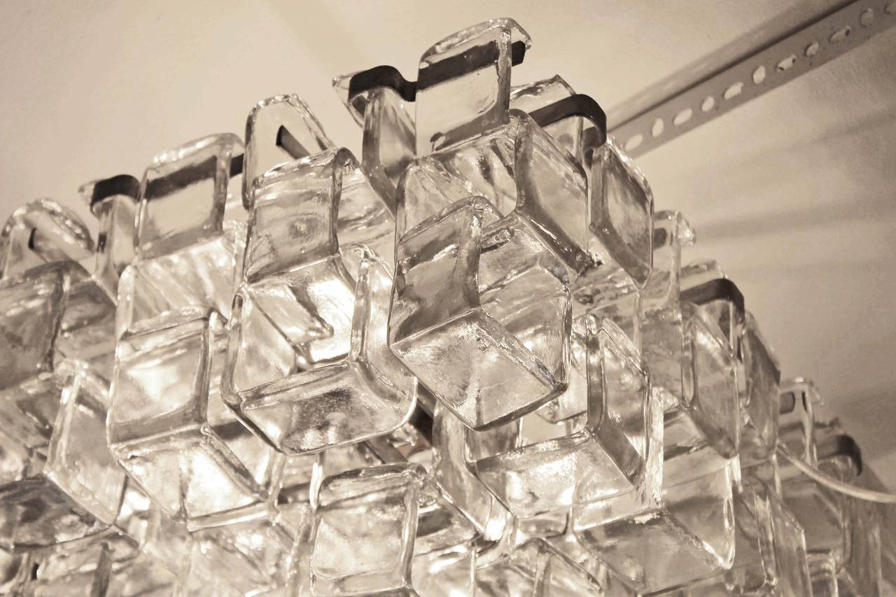 Pair of chandeliers made with squared interlocking glasses, disposed in three levels. Glasses are suspended from a nickel plated structure. The interlocking glasses create a wonderful visual effect. The chandelier has eight candelabra socket that