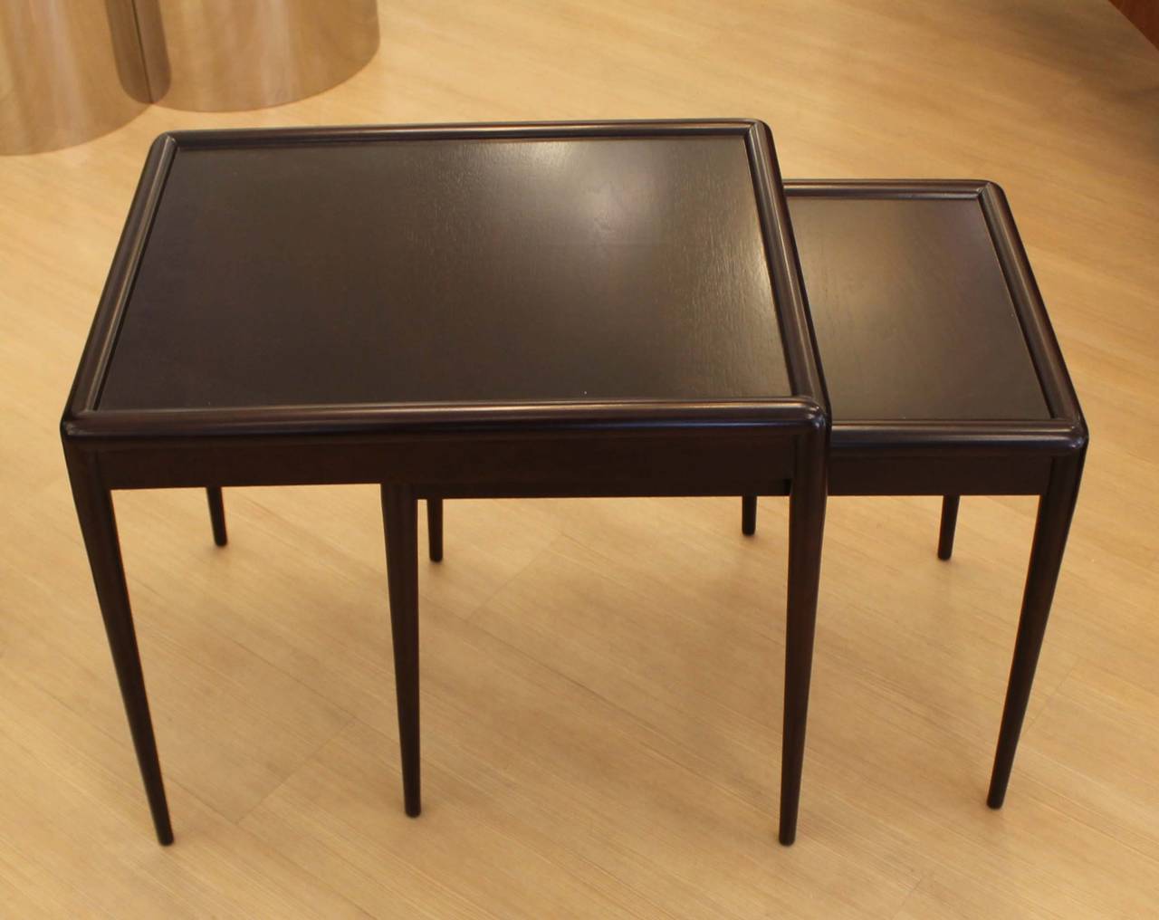 Pair of 1950s Robsjohn-Gibbings for Widdicomb nesting tables. Simple and elegant design featuring a framed top and tapered legs. Finished in a lacquered semi-matte dark walnut stain. Marked under the top. Measurements below are for the largest table.
