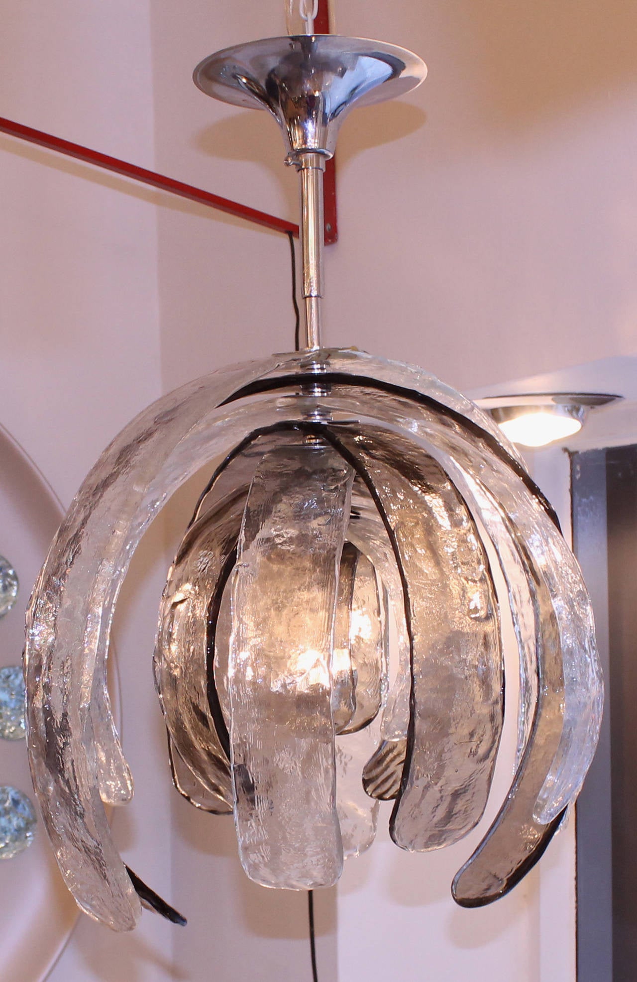 This pendant is one of the most striking designs by Nason for Mazzega. It is made with nine semi-circular handblown glasses of different sizes, alternating clear, rich texture glasses with gray ones. It holds one 100W regular light socket.
Mazzega
