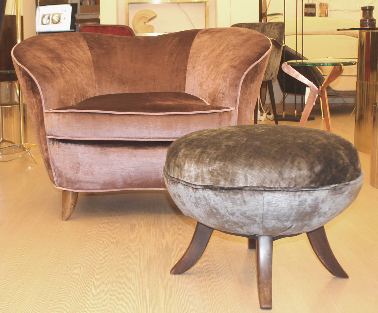 Pair of comfortable curvaceous armchairs with one round ottoman. Tapered wood legs. Legs are presently stained dark for the ottoman and light for the armchairs but can be changed as per the clients preference. One armchair has been re-upholstered