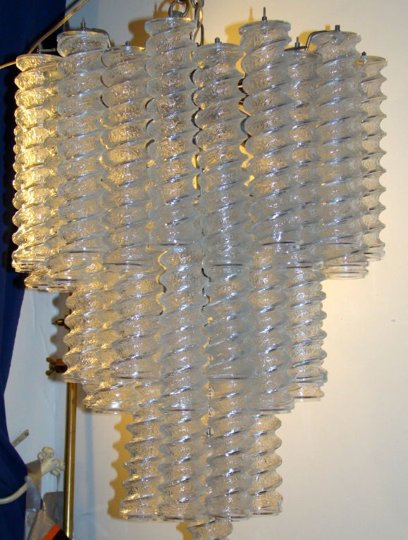 This rare chandelier is made with three rows of clear spiral glasses hanging from a nickel plated metal structure. It holds 9 regular light sockets. Rewired.