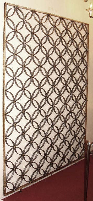 Elegant 50's metal screen made with an iron frame containing circular aluminum elements held together by brass bolts. Three feet. An ideal piece to divide two environments within the same room