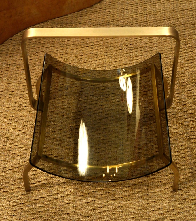 The curved solid brass structure creates a receptacle for the smoked glass. Simple yet very sleek and elegant. Can also be used as a wood tray for fireplaces.