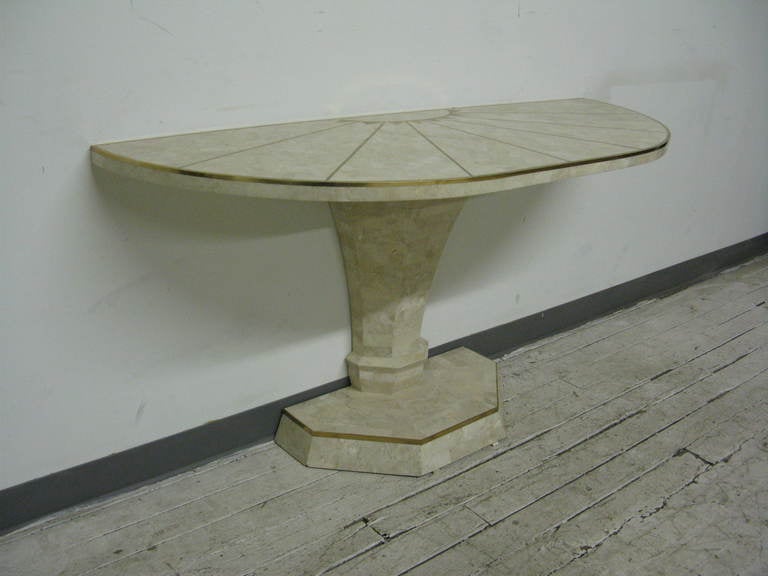This is a lovely Italian style demilune console table created for export by Maitland-Smith in neoclassic style with tessellated fossil stone and brass inlay in a sunburst pattern on top and around the base.