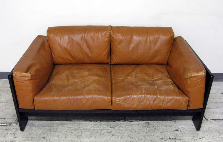 Beautiful Bastiano loveseat with dark rosewood frame and rich brown leather cushions. Designed by Tobia Scarpa for Gavina, the piece retains its original upholstery and finish. Gavina label attached to upholstery and frame. Elegant line and