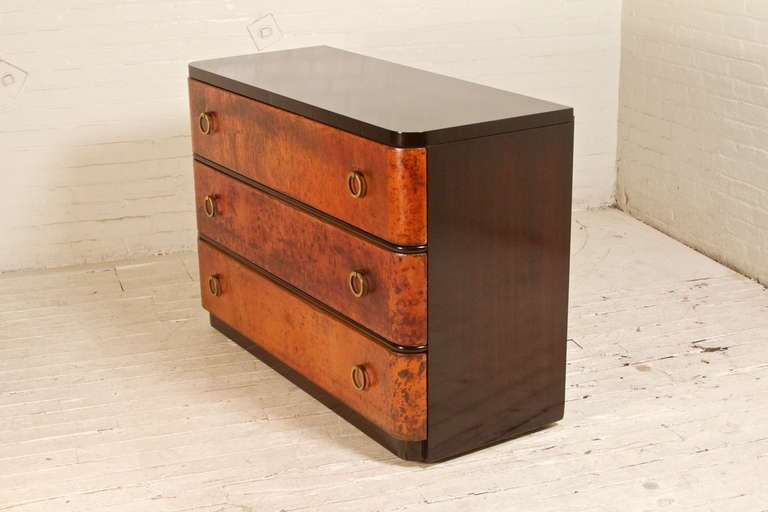 This stunning, Art-Deco style gentlemen's dresser, features a beautifully-refinished walnut veneer, original solid brass hardware, and three spacious drawers wrapped in distressed leather. Boasting classic proportions and handsomely-rounded corners,