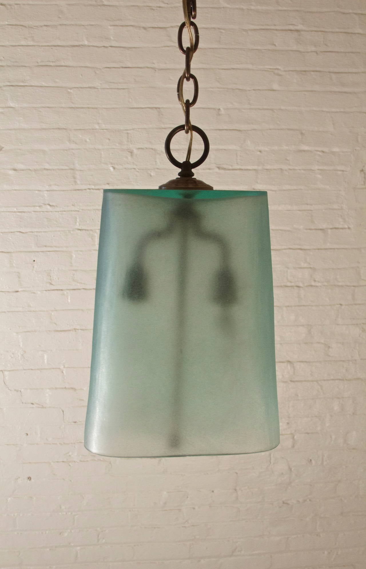 Unique Italian pendant light with gracefully-shaped Corroso glass form in subtle semi-transparent green tone and two symmetrical bronze branches with floral collars; supported by bronze chain. Original fixtures-working condition.