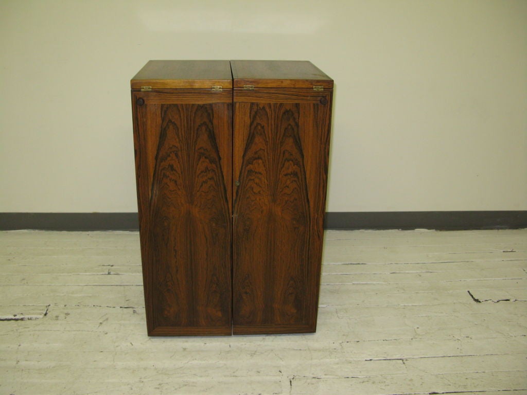 Great looking Danish useful 2 section with key lock folding dry bar cabinet on wheels beautifully veneered in Brazilian rosewood ,on each compartment with drawers and pull out metal trays with two flip out top serving island.