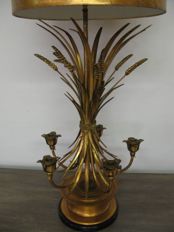 Large antique gold leaf colored, gilded metal table lamp. The shade is original. It features candle holders that flare out from under the beautiful wheat shaped decorations, which are bound to the center. Item will serve as a dramatic centerpiece to