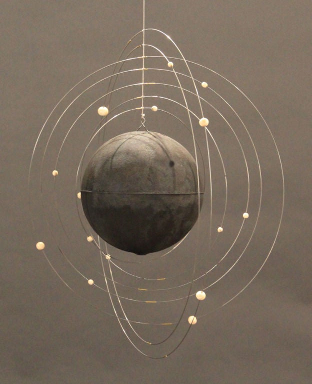 Unique and decorative mobile made by an artist in Belgium.  Tiny beads orbit the large black center to mimic orbiting moons around a planet. Adjustable hanging height.