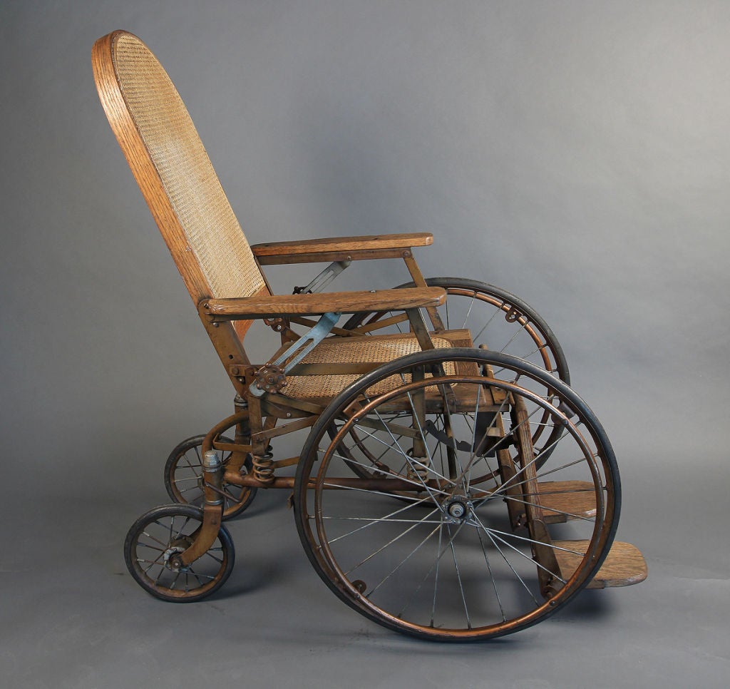 Very unusual wheelchair. Perfect comfortable seating. Oak wood with cane seat and back. Wheels are rubber and the hand held wheels are metal. Two large wheels and two small wheels in the back that swivels for easy steering.