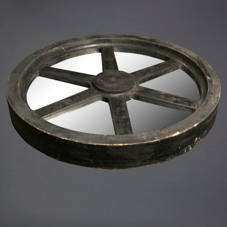 A unique rustic piece to add to your decor. A vintage wagon wheel, embedded with mirrors, covered with glass, and atop a steel platform. This short and stout coffee table brings a natural, rugged, yet chic ambiance to the room. Sculpture piece not