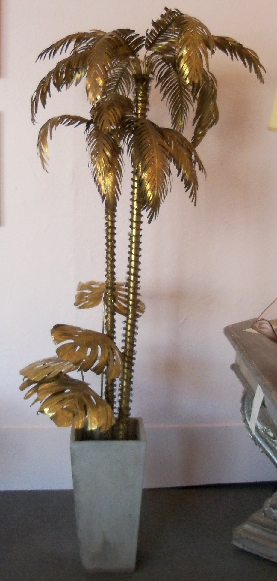 Stunning and chic Maison Jansen brass palm tree sculpture having upper elongated pinnate leaves, which extend from thin brass tubes and arc gracefully over two brass trunks wrapped in coiled brass wire. The lower lobed leaves are set in thin brass