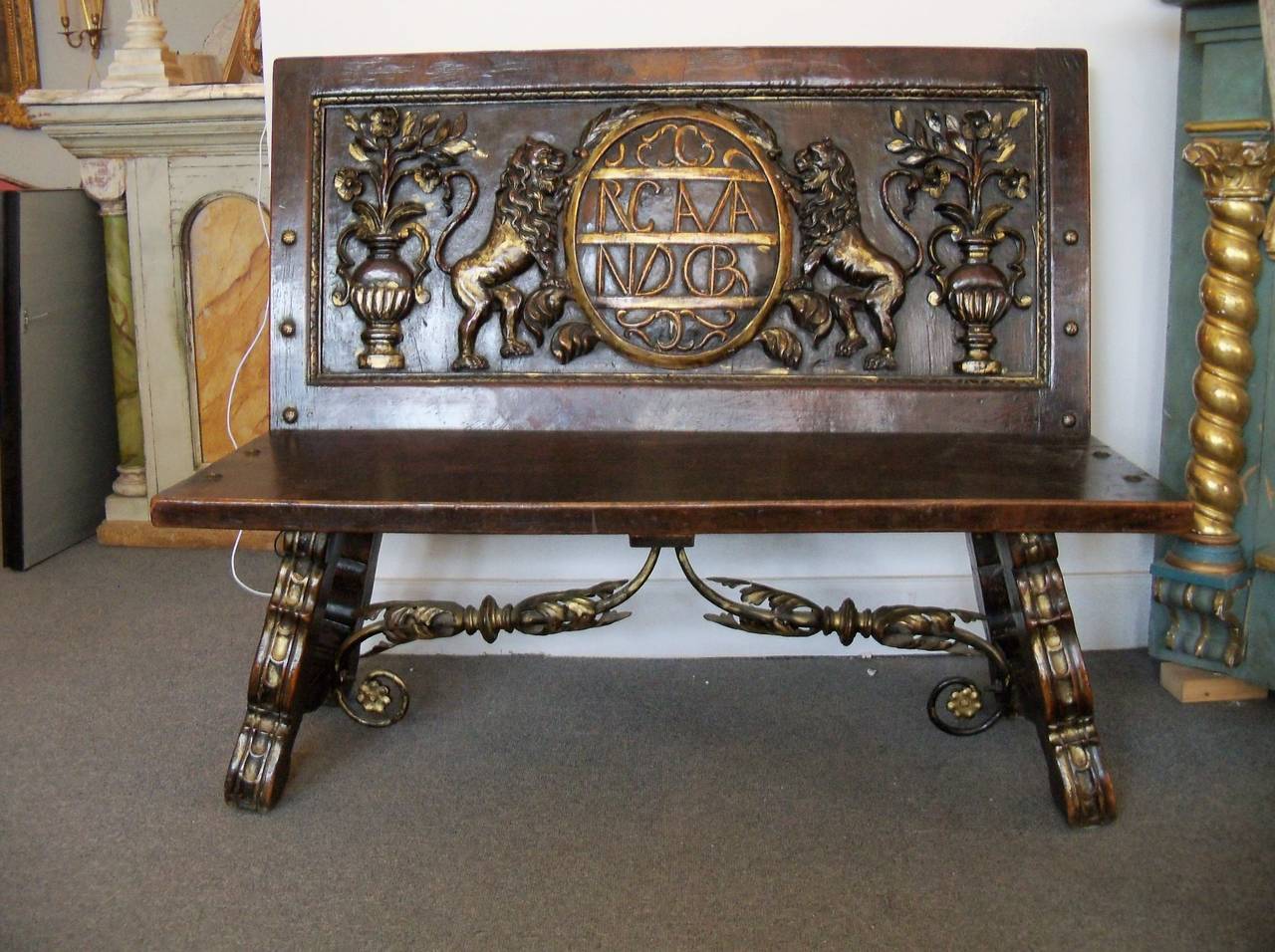 Highly decorative carved stained walnut  bench with gilt accents;  Italy 19thc.  A gilded iron stretcher adorned with gilded iron leaves supports the seat and legs;  further support is provided by an iron angle brace bolted to the back and underside