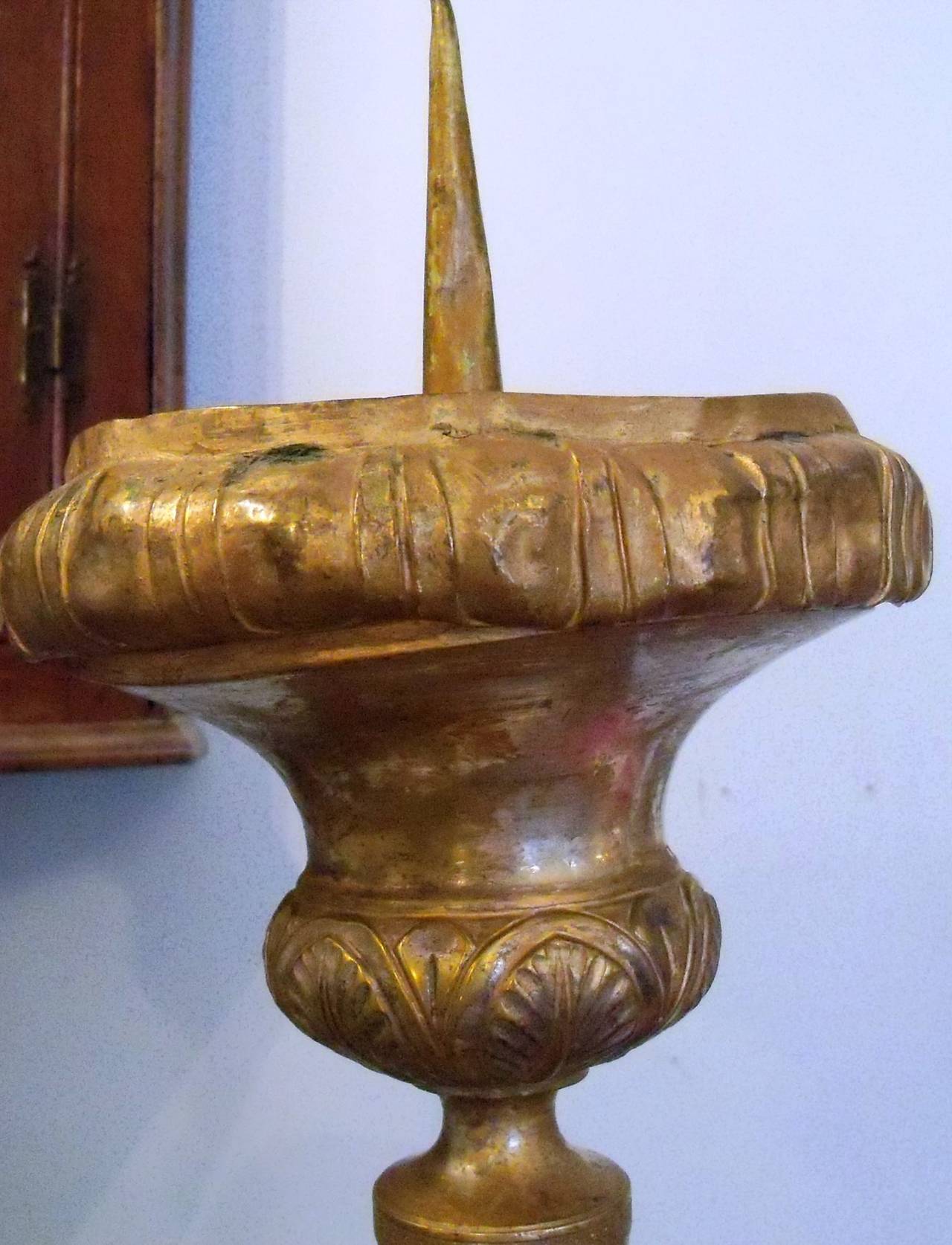 Two similar but not identical French church candlesticks. The one pictured on the left is silvered brass and heavily ornamented with neoclassical features including drapery, Greek keys and palmettes and with religious symbols including a lamb,