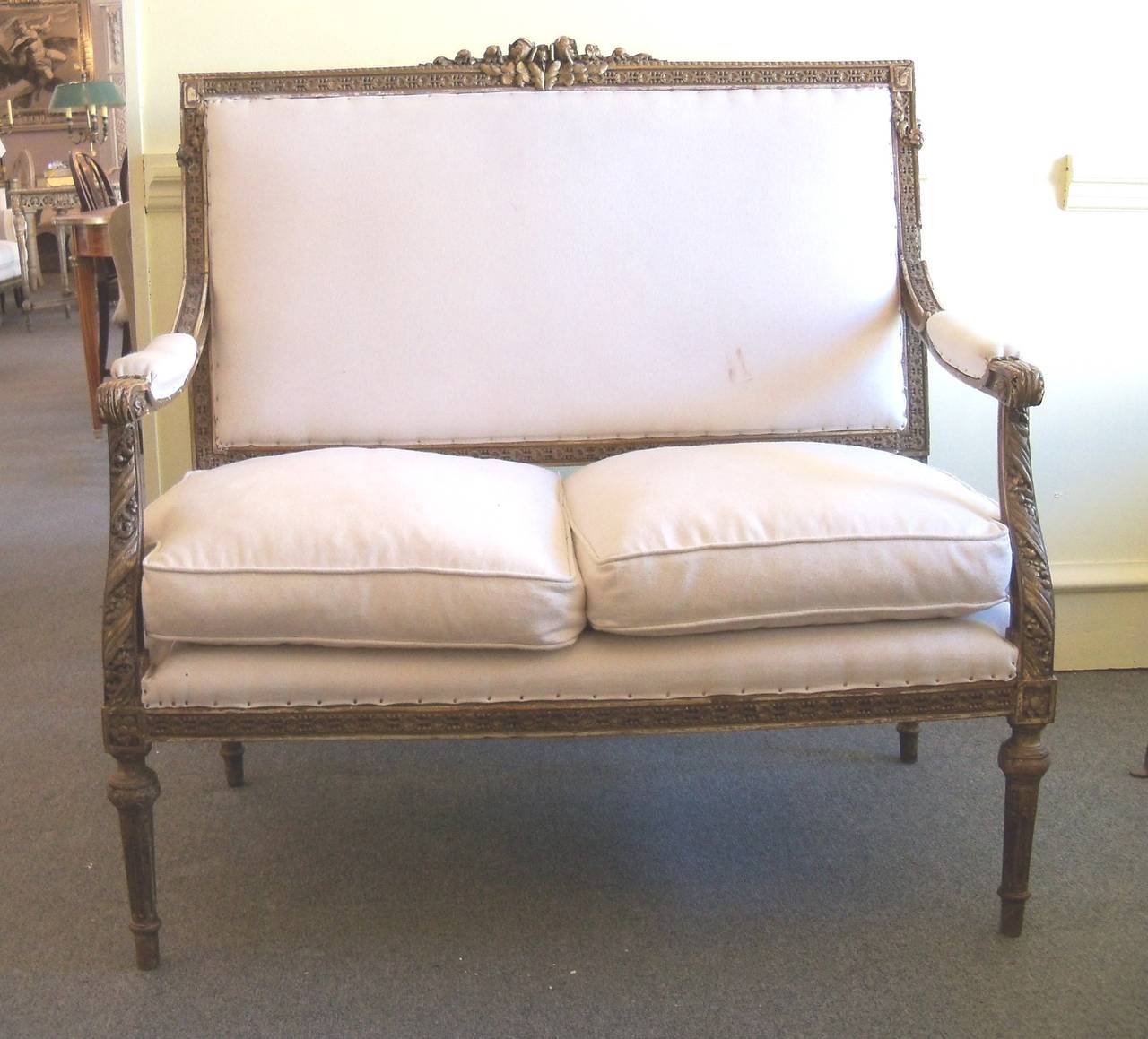 This lovely piece has a carved wood frame decorated with rosettes, garlands, fluting, beading and additional motifs.  The back and seat are relatively newly re-upholstered as are a portion of the arms. The seat also has two seat cushions.
