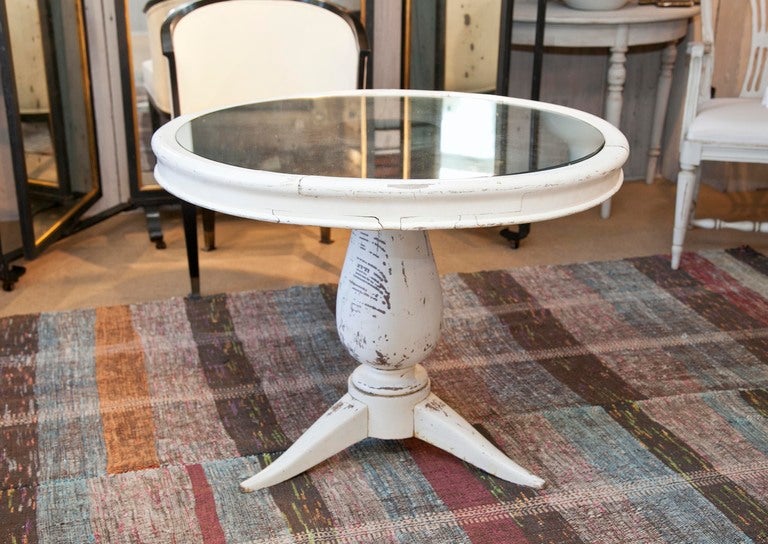 Table in distressed oyster paint with tripod base and inlaid mirrored glass top.