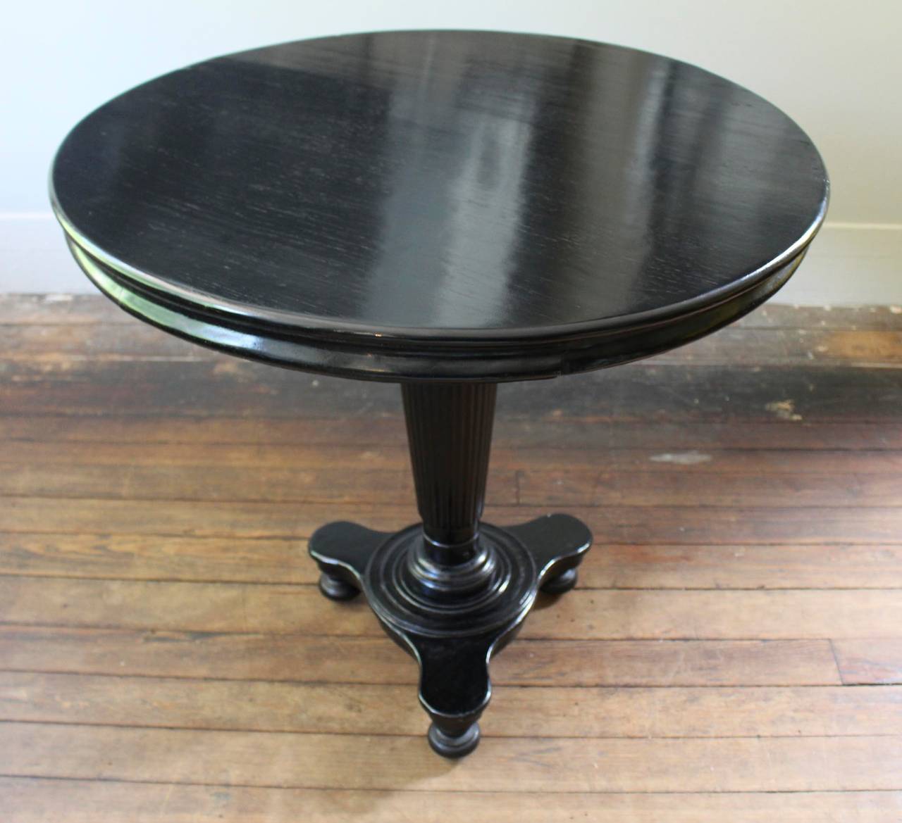 Ebonized round table with fluted tripod pedestal base.