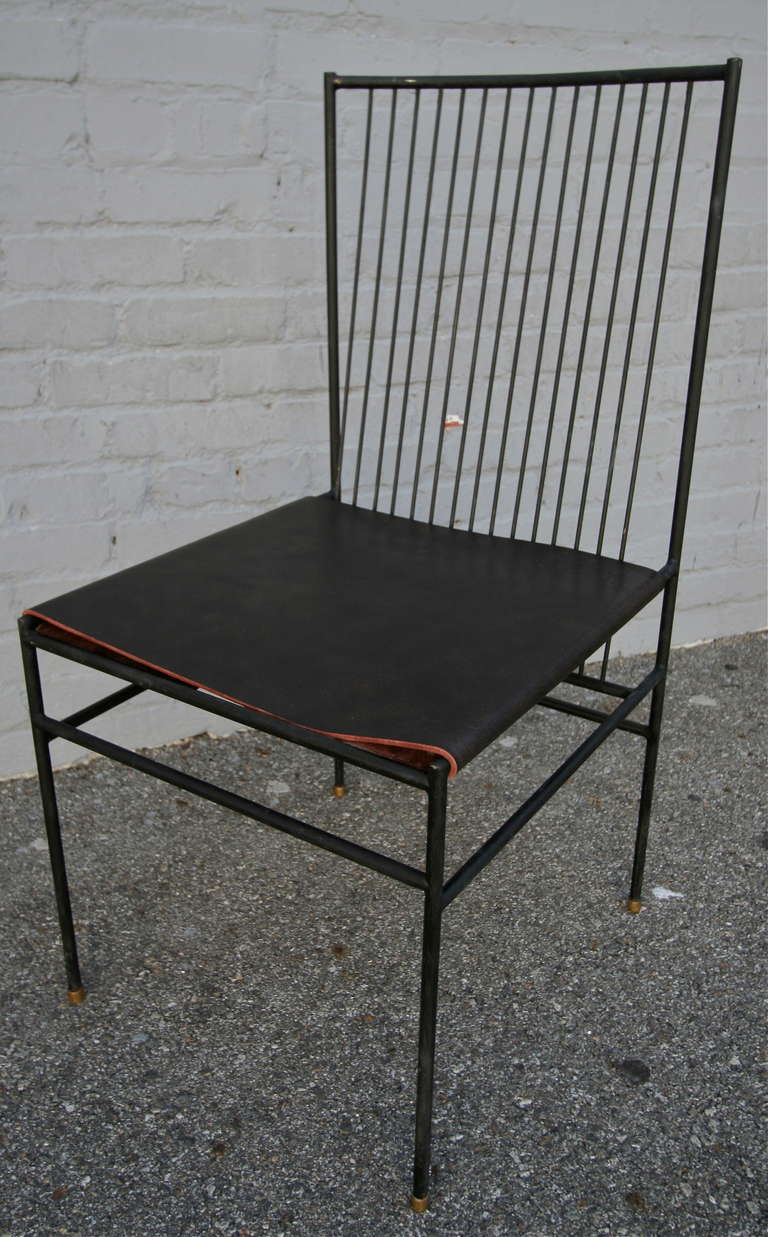 Set of ten iron dining chairs with leather seats and brass feet in the style of Joaquim Tenreiro.