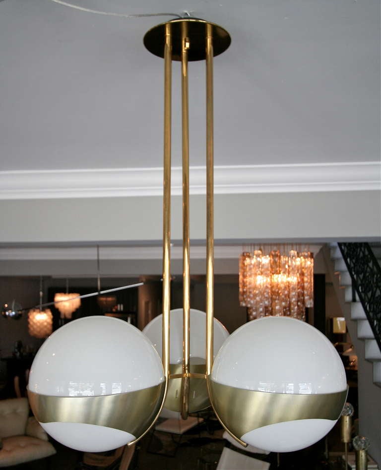 1970s Lamperti chandelier with three large white globes nestled in a brass frame.